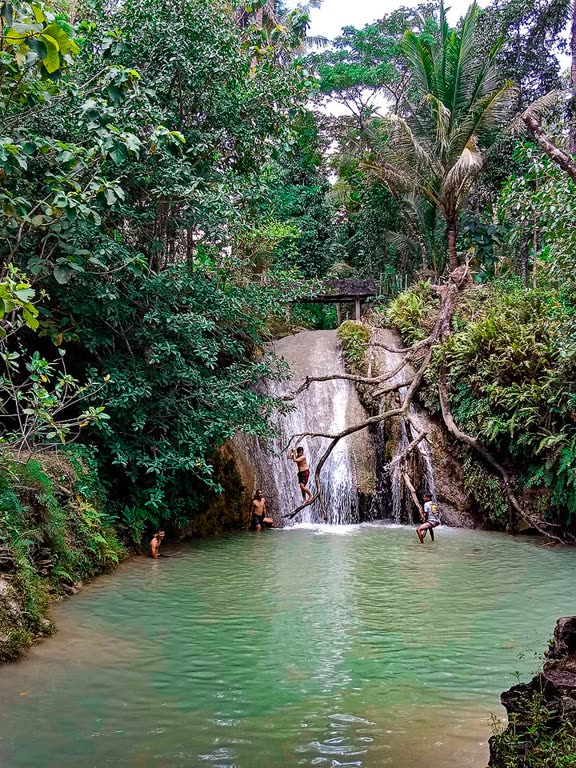 Kolam hijau Kedung Pengilon tempat warga berenang, diapit dinding batu dan pepohonan.